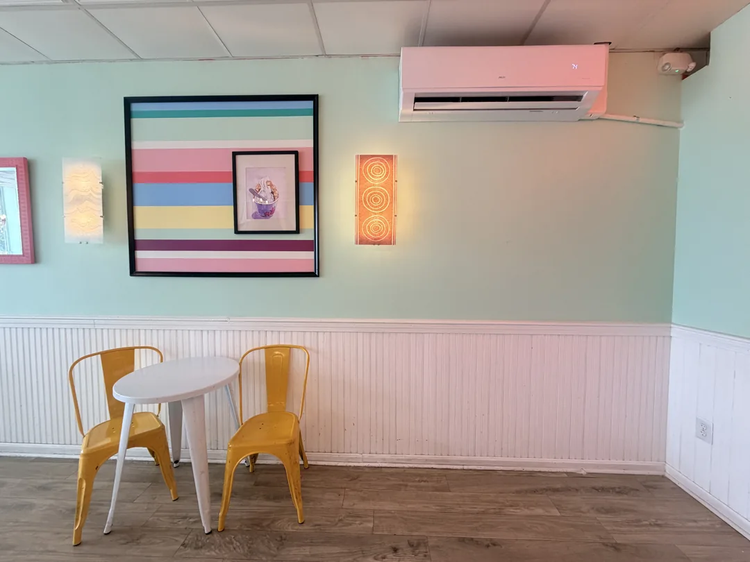 Finished indoor heat pump above a table and yellow chairs at Wally’s.