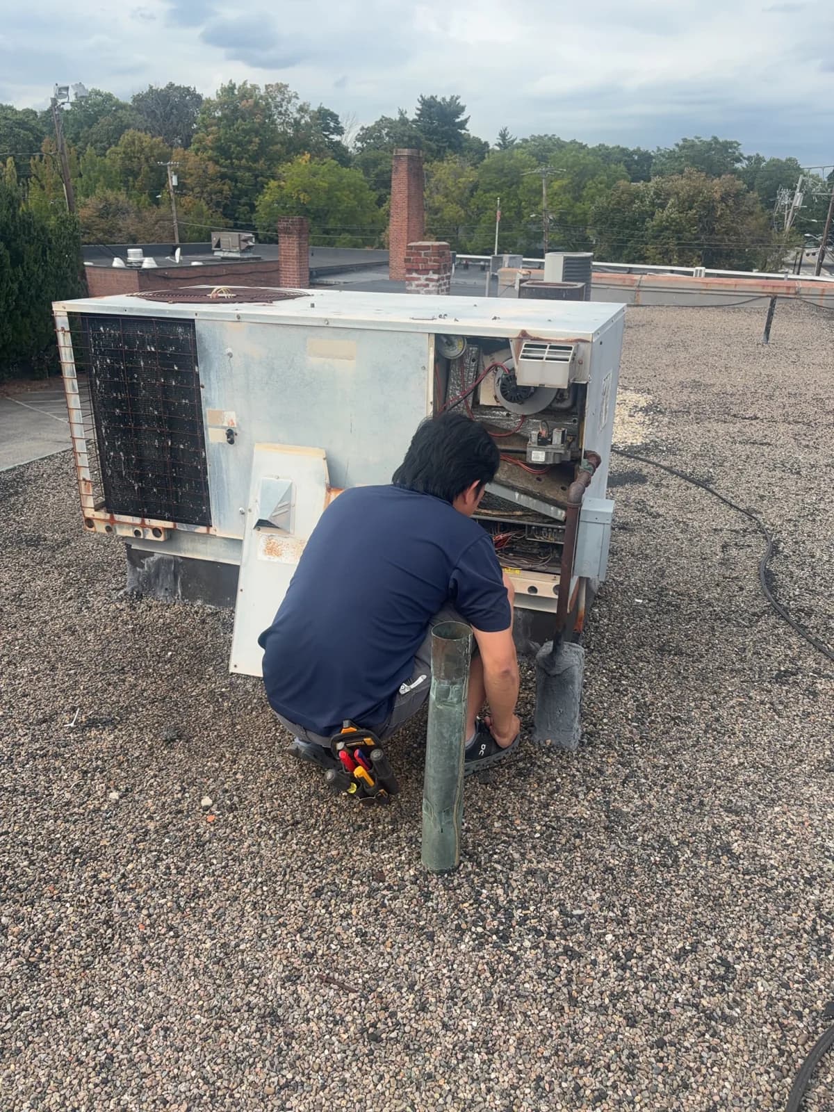 An Advanced Ductless technician examining the older rooftop equipment at the Wally’s project.